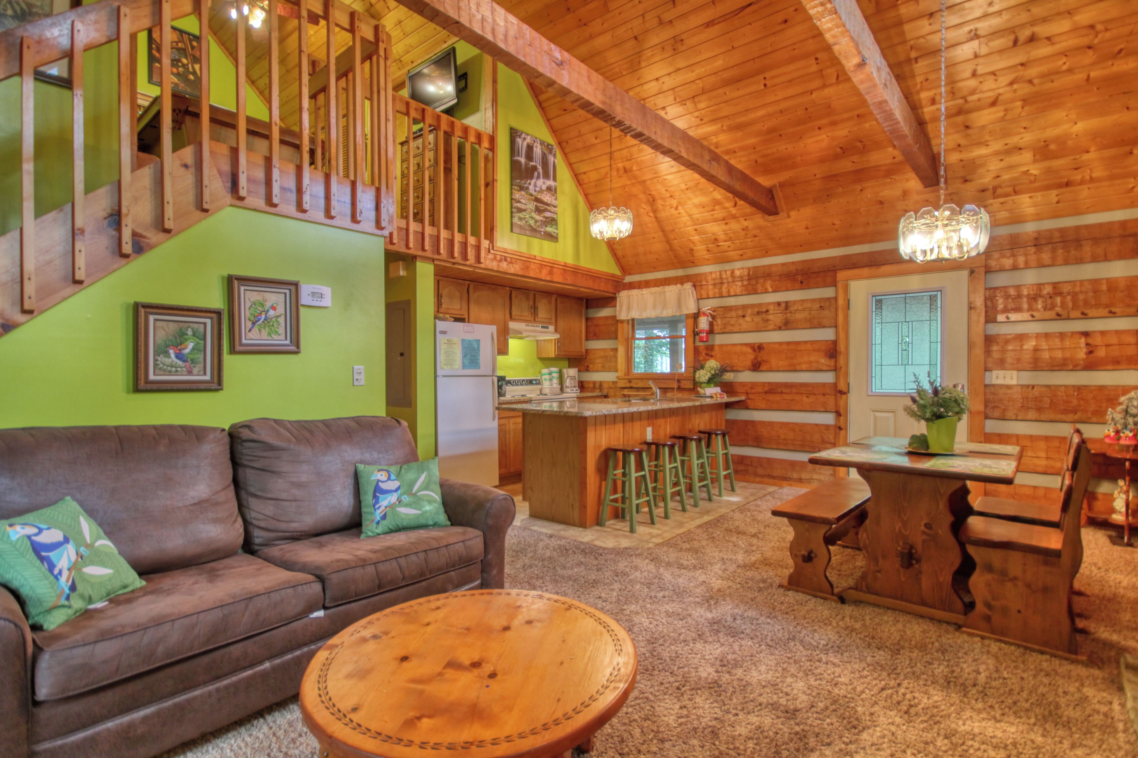 A cozy log cabin interior with a living room, kitchen, and dining area.