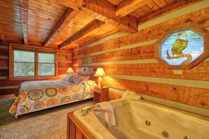 Una habitación de cabaña acogedora, con cama, bañera y ventana con techo de madera.