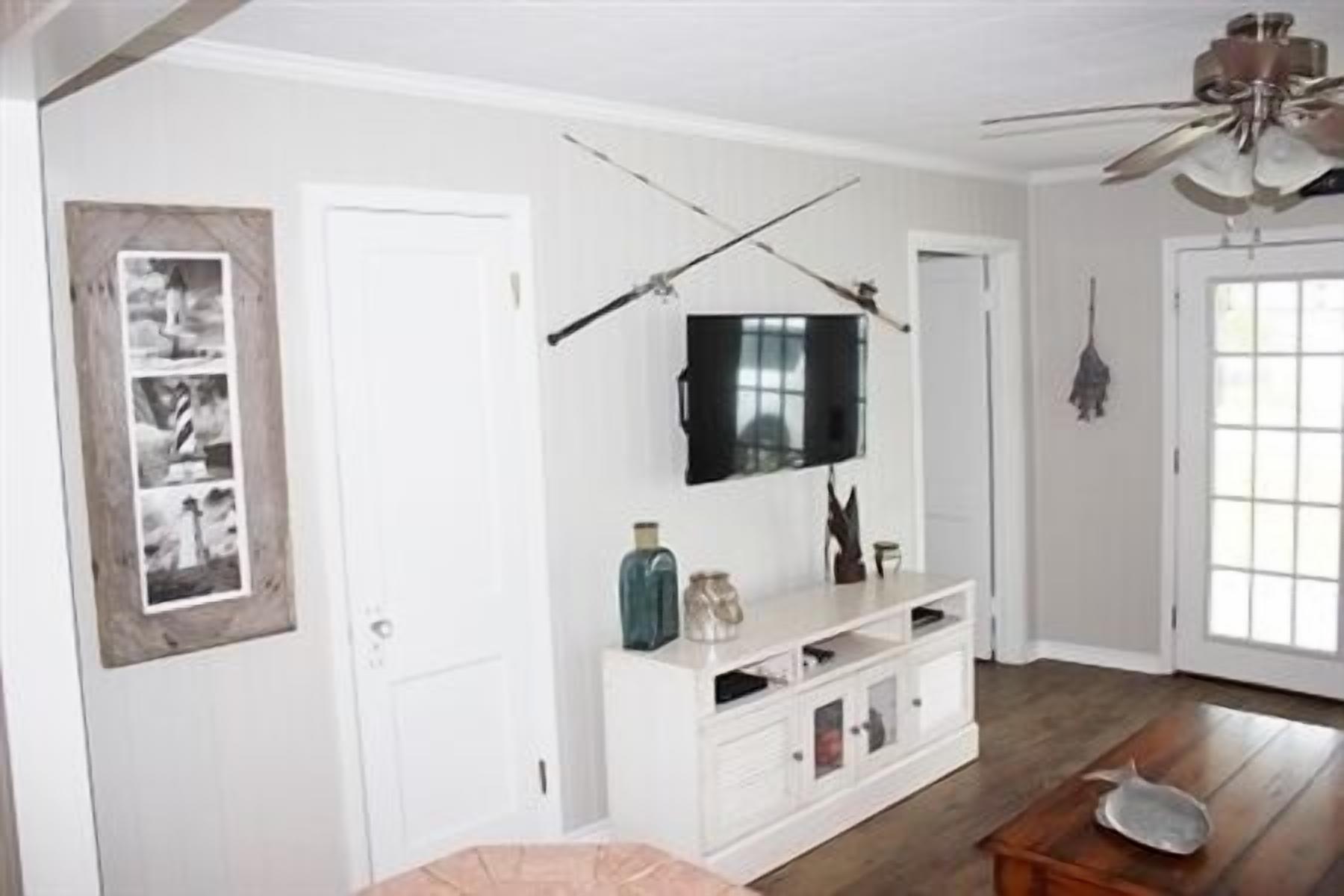 A living room with a white entertainment unit, a ceiling fan, and a door with a view.