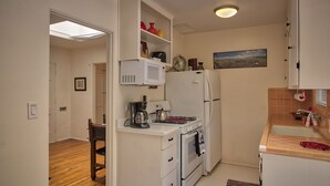 A compact kitchen with white appliances, a dining area, and a view of the city through a skylight.