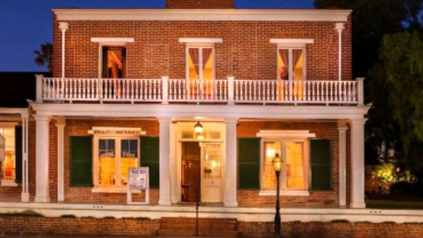 A two-story brick building with a balcony, a front entrance, and a sign that reads "Whale & Crockett's".