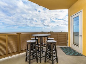 A balcony with a view of the ocean, wooden railings, and a door with a window.