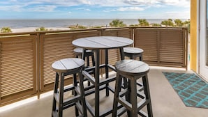 Ein Balkon mit Tisch und Stühlen mit Blick auf den Strand.