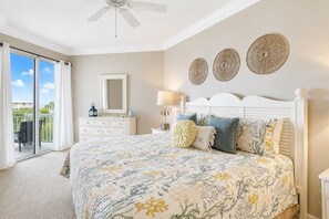 Une chambre à coucher avec un lit, une commode, un miroir et un ventilateur de plafond.