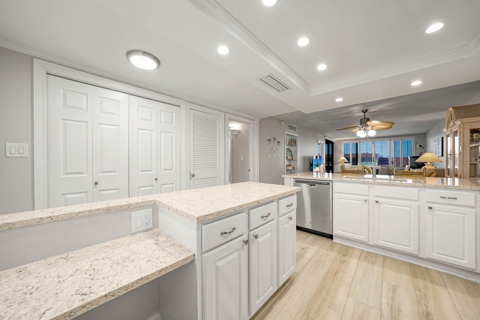 A modern kitchen with white cabinetry, granite countertops, and a built-in dishwasher.