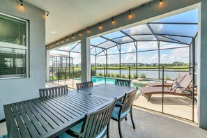 A covered patio with a pool, outdoor seating, and a view of the landscape. - EV_4795 - 6BR / 5BA Storey Lake Villa near to Disney, Private Pool & Games Room (Kissimmee)