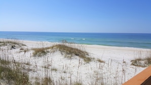 Une plage de sable blanc avec une végétation clairsemée.