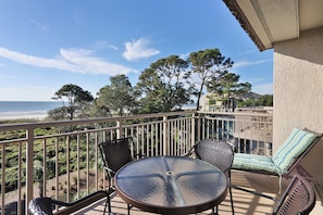 Enjoy the serene beach view from this balcony with a round table and two comfortable chairs.