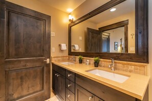 A bathroom with two sinks, a large mirror, and dark wooden cabinetry. - Base Village Loft 109 | At The Base Area | Hot Tub | Private Balcony (Winter Park)