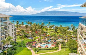 A resort with a pool area, palm trees, and a view of the ocean. - Maui Resort Rentals: Honua Kai Konea 831 - Stunning 8th Floor Ocean View Studio (Lahaina)