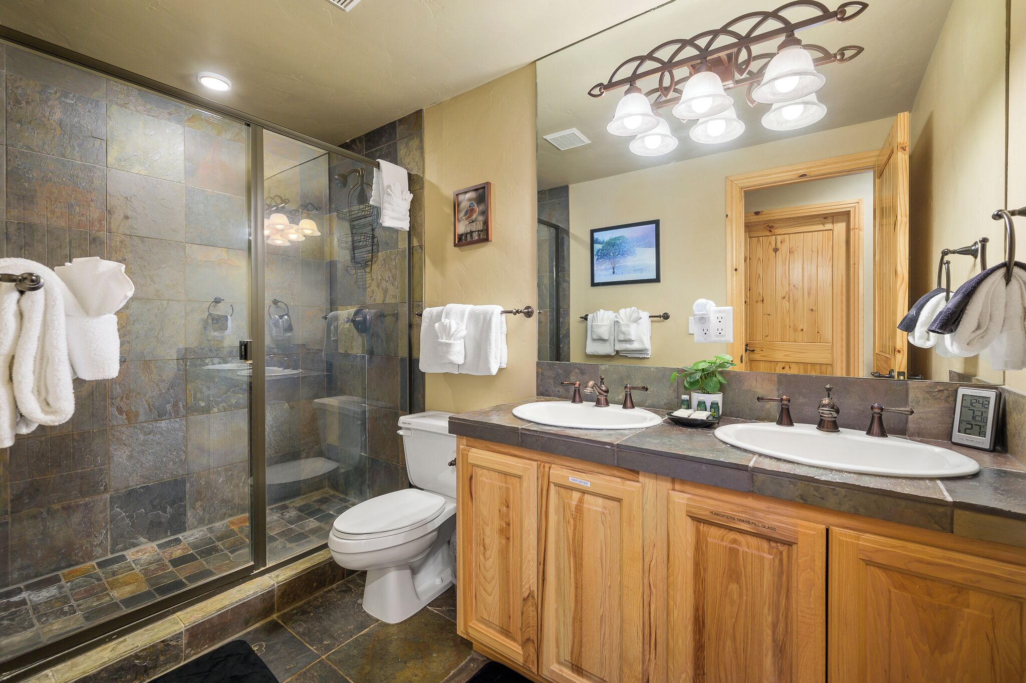 A modern bathroom with a glass shower enclosure, a double sink vanity, and a large mirror.