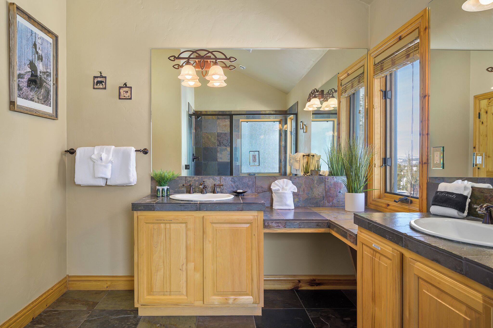 Un bagno moderno con un ampio specchio, mobili in legno e un piano in granito.