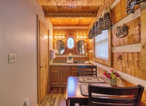A wooden interior with a kitchen area, wooden ceiling, and a dining table with chairs.