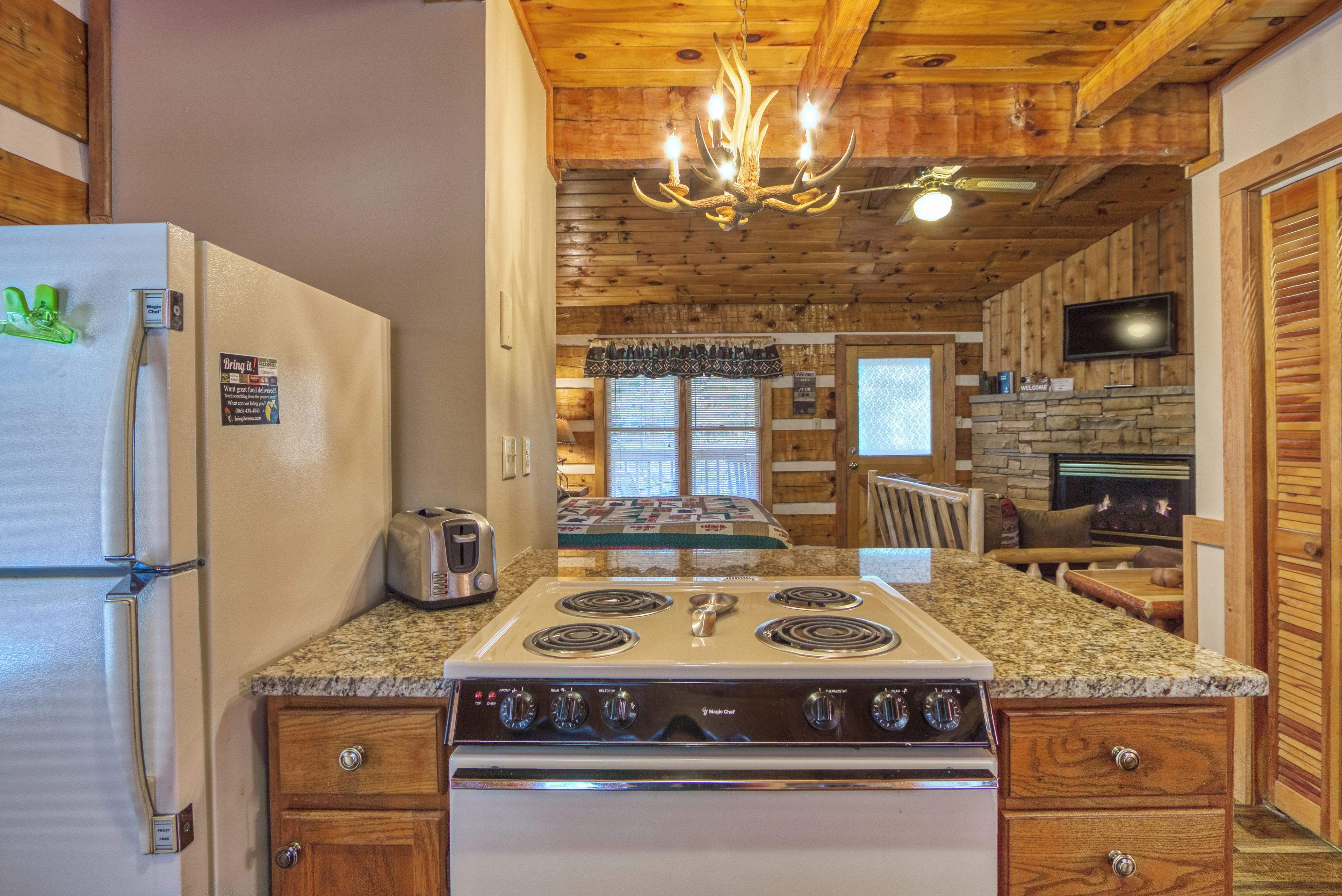 A kitchen with a stove, refrigerator, and wooden ceiling.