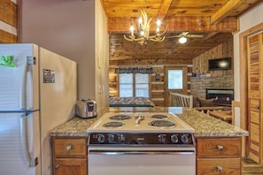 A kitchen with a stove, refrigerator, and wooden ceiling.