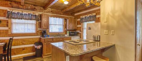 A kitchen with wooden cabinets, a granite countertop, a built-in stove, and a chandelier.