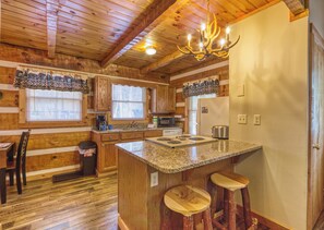A kitchen with wooden cabinets, a granite countertop, a built-in stove, and a chandelier.