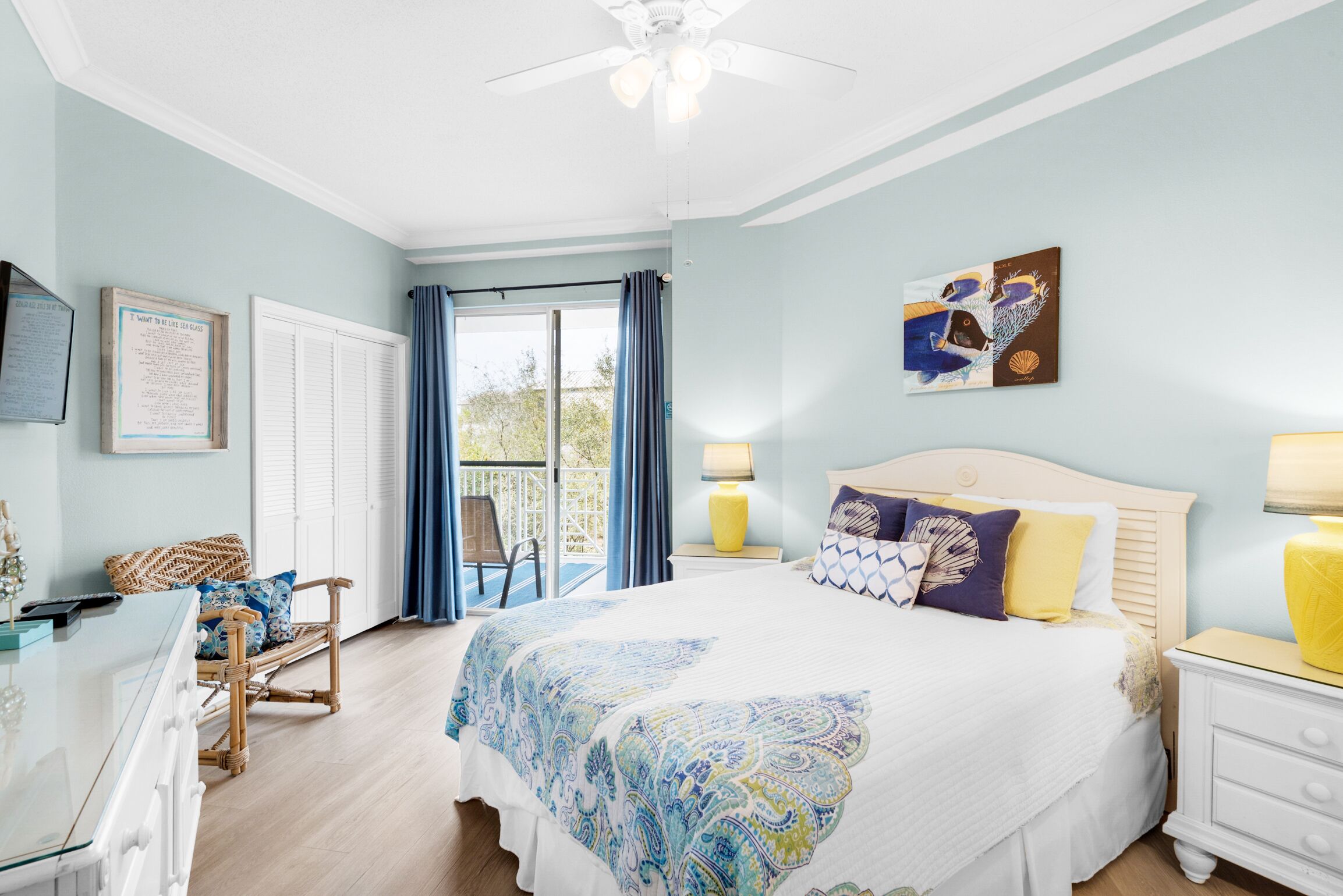 A bedroom with a bed, a chair, a desk, and a balcony.