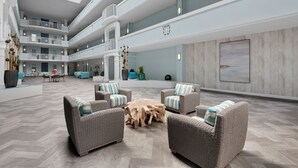 Eine geräumige Lobby mit mehreren Sitzbereichen, einem zentralen Couchtisch und einer hohen Decke mit Oberlichtern.