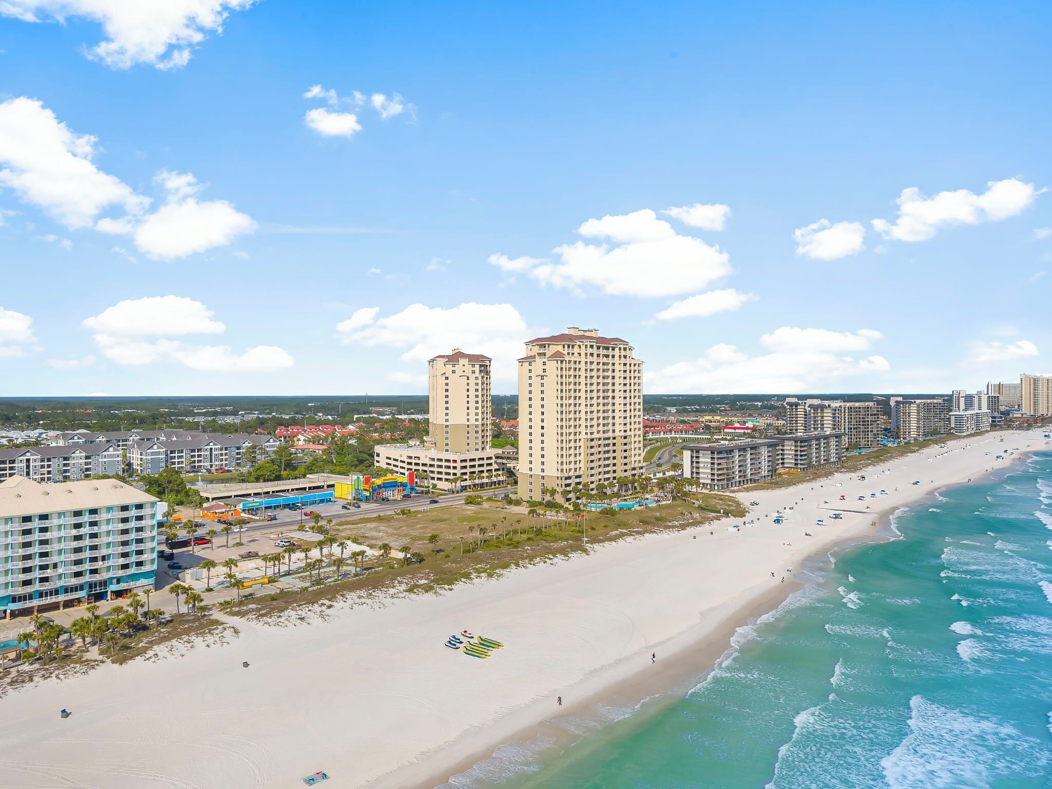 Eine Küstenstadt mit Hochhäusern, einem Sandstrand und einem klaren, blauen Himmel.