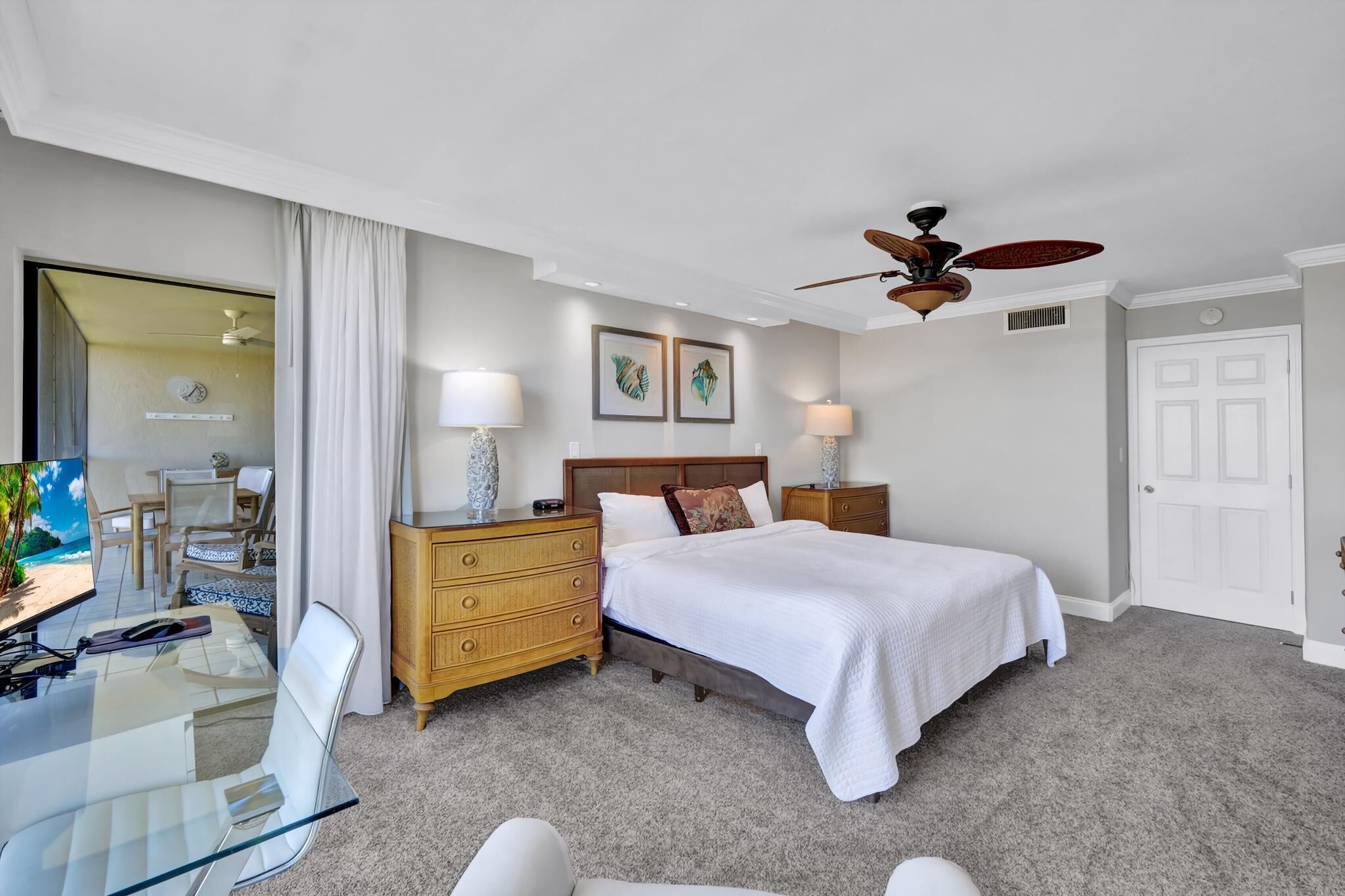 Una habitación de hotel con cama, escritorio, silla, cómoda y ventilador de techo.