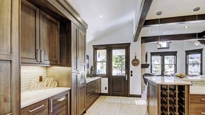 A kitchen with dark wooden cabinets, a white countertop, and a wine rack.