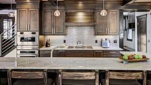 A modern kitchen with dark wooden cabinets, stainless steel appliances, and a marble countertop.