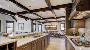 A modern kitchen with a large island, wooden cabinets, and a gas stove.