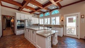 A spacious kitchen with white cabinetry, a large island, and a brick floor. - 20-Acre Estate w/ Pool, Games & Meeting Space (Oakland)