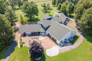 A large, multi-story building with a symmetrical roofline, surrounded by a well-maintained lawn and trees. - 20-Acre Estate w/ Pool, Games & Meeting Space (Oakland)