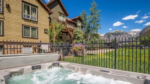 A hot tub with a wooden deck and a sign indicating emergency procedures. - Ski-in/Ski-Out Ground Floor Easy Access Ski Condo (Telluride)