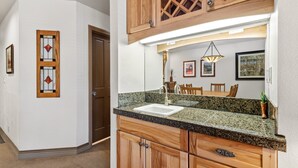 A kitchen with granite countertops, wooden cabinets, a sink, and a dining area with chairs. - Ski-in/Ski-Out Ground Floor Easy Access Ski Condo (Telluride)