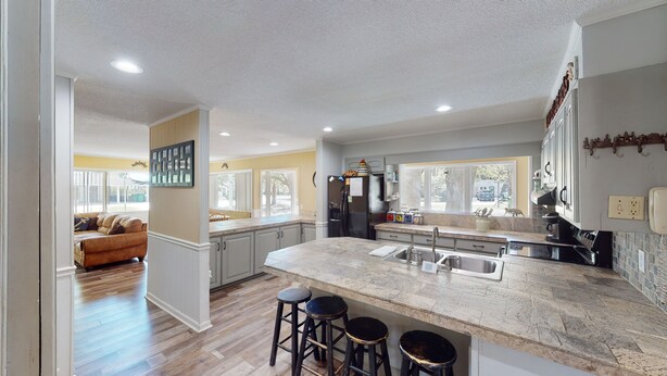 A modern kitchen with a large island, bar stools, and a view of the outside.