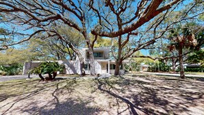 A modern two-story house with a spacious front yard, surrounded by mature trees.