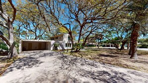 A single-story building with a garage, surrounded by trees and a clear sky.