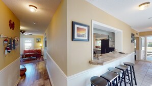 A kitchen with a bar area, wooden flooring, and a view into the living room.