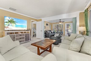 A living room with a large TV, a wooden coffee table, and a grey sofa.