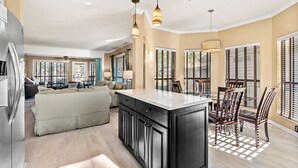 Una cocina moderna con una isla central, electrodomésticos integrados y un comedor con sillas y una mesa.