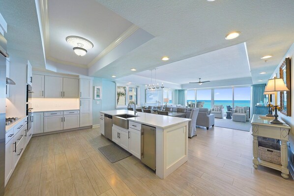 A spacious kitchen with a large island, modern appliances, and a view of the ocean.