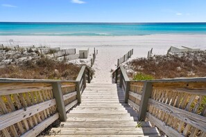 A wooden staircase leading to a beach with clear turquoise waters.