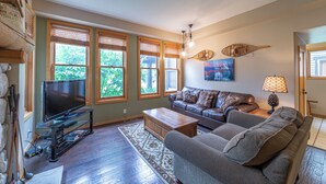 A living room with a flat-screen TV on a stand, a sofa, a coffee table, and a patterned rug. - Scenic Family-Friendly Condo w/ Spa 307 (Mammoth Lakes)