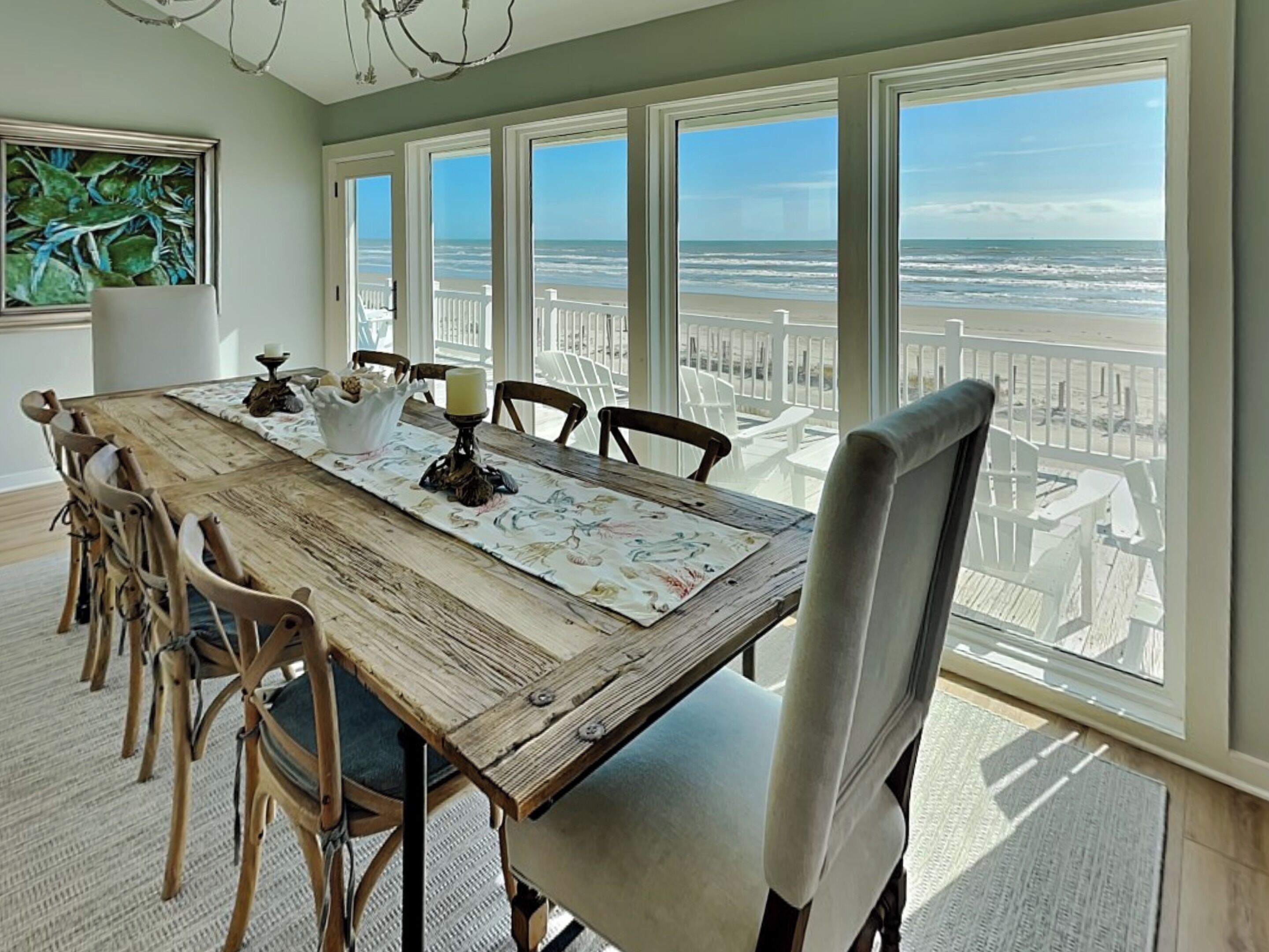 Un espace repas comprenant une grande table, des chaises et une vue sur la plage grâce à de larges fenêtres.