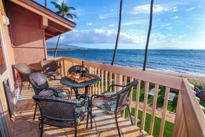 Enjoy the ocean view from this balcony with wicker chairs and a small table.