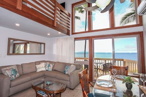 Relax in this inviting living area with a comfortable sofa, glass coffee table, and sliding door leading to an ocean-view deck.