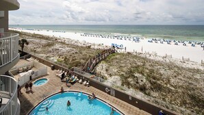 A pool area with a view of the beach, lounge chairs, and a wooden deck leading to the beach. - Island Princess 509🌊Gulf Front🏖️Free Beach Setup (Fort Walton Beach)