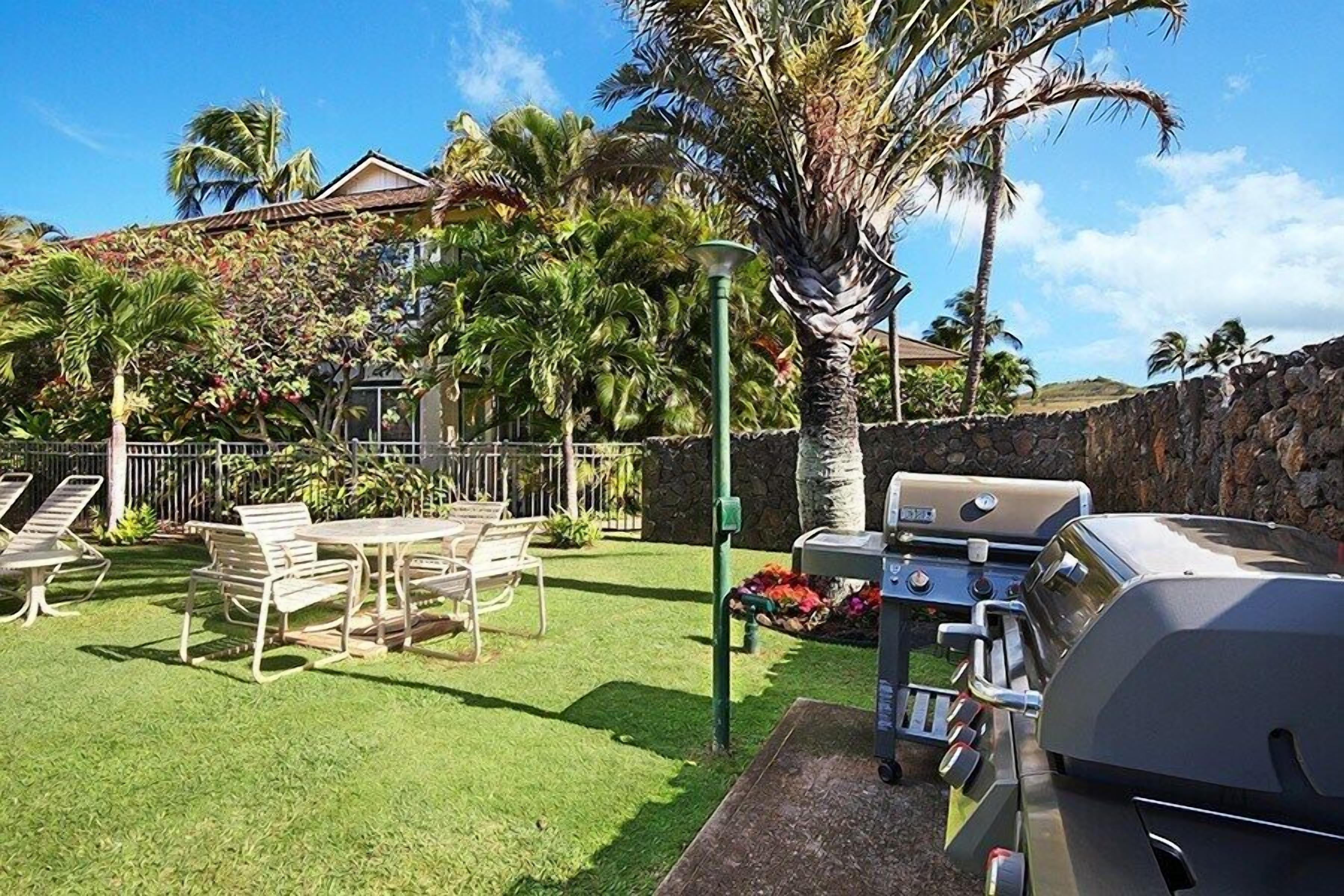 Ein Garten mit Grill, Stühlen und einem Tisch.