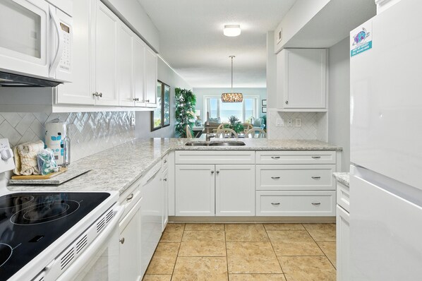 Una cocina moderna con armarios blancos, una estufa negra y un salpicadero de azulejos.