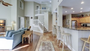 A spacious living area with a sofa, a small table, and a staircase leading to a balcony.