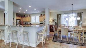 A spacious kitchen with wooden cabinets, a large island with bar stools, and a dining area with a chandelier.