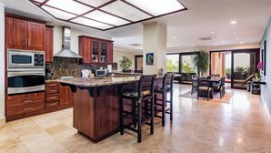 Una cocina amplia con una isla central, hornos integrados y un ventanal grande.